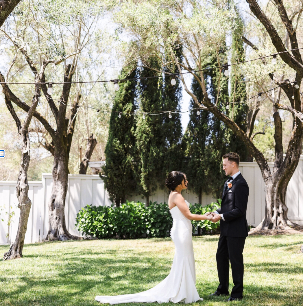 Couple sharing a first look in the Olive Grove beneath string lights