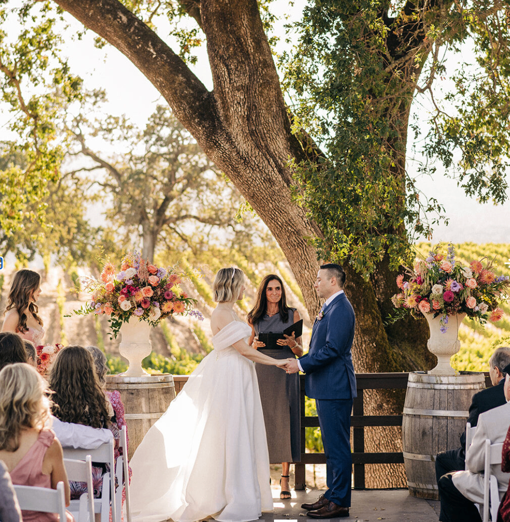 Wedding ceremony in the amphitheater framed by colorful florals and vineyard views